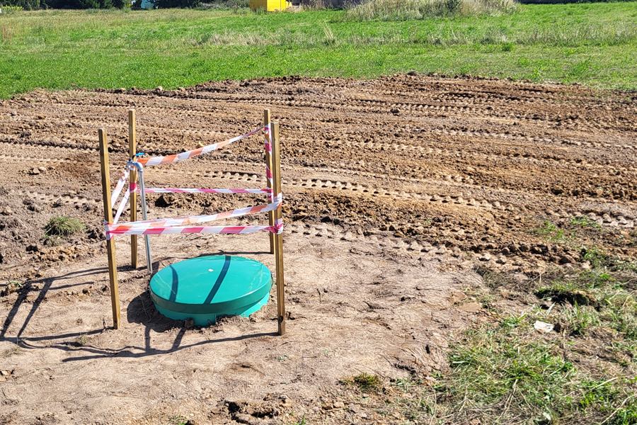Zabezpieczona taśmą studzienka na działce po zakończeniu odwiertu