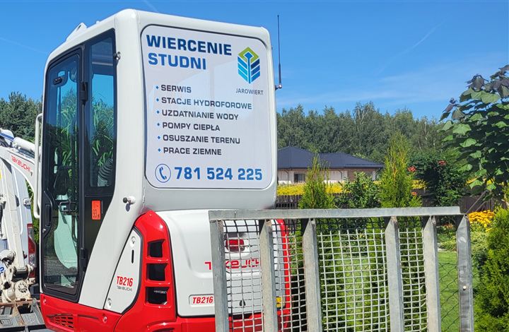 Minikoparka Jarowiert z listą usług i numerem telefonu na kabinie
